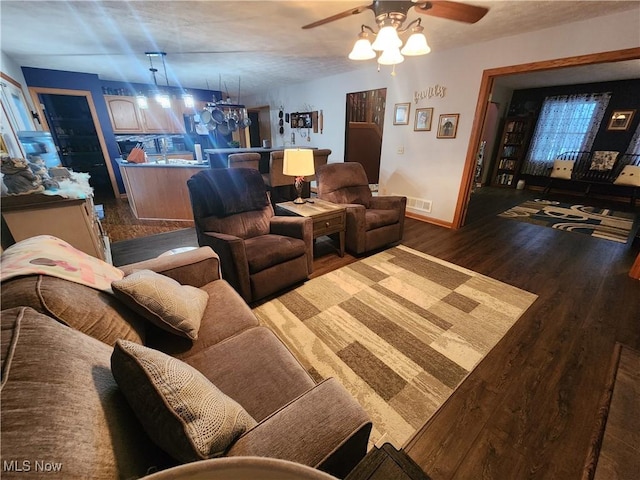 living room featuring ceiling fan and dark hardwood / wood-style flooring