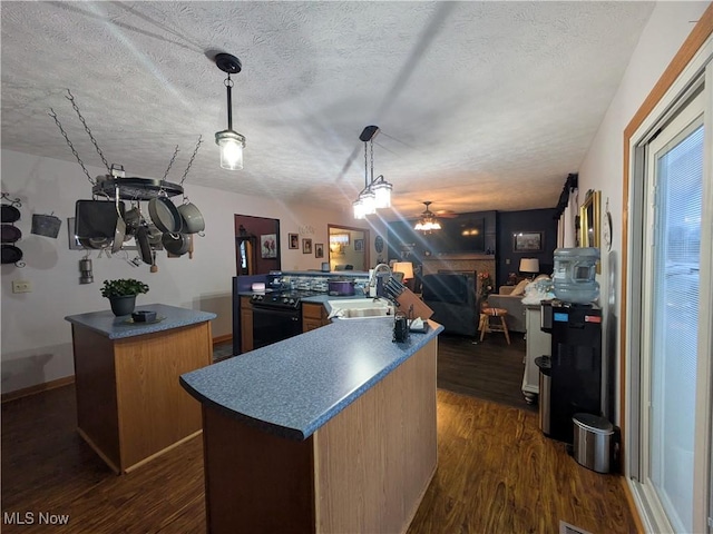 kitchen featuring sink, dark wood-type flooring, black electric range, pendant lighting, and a kitchen island