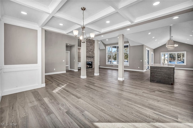 unfurnished living room with a stone fireplace, sink, hardwood / wood-style floors, and a notable chandelier