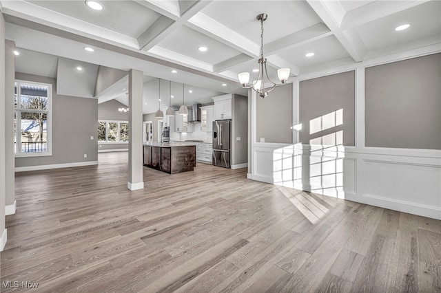 unfurnished living room featuring beamed ceiling, light hardwood / wood-style floors, and a notable chandelier