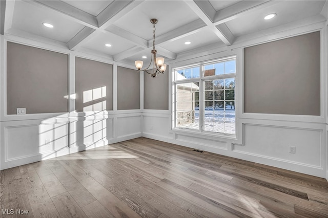 unfurnished dining area with beam ceiling, a chandelier, and coffered ceiling