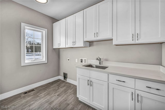 clothes washing area featuring hookup for an electric dryer, cabinets, sink, and washer hookup