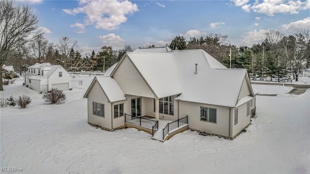 snow covered property with a garage and an outbuilding