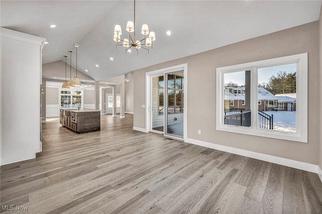 unfurnished living room featuring a healthy amount of sunlight, light hardwood / wood-style floors, and a notable chandelier