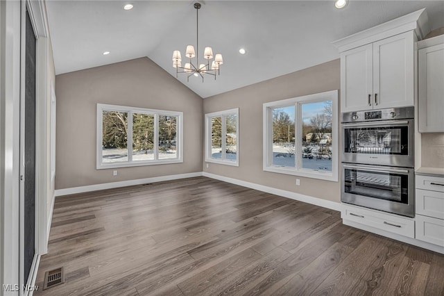 kitchen with double oven, a chandelier, decorative light fixtures, wood-type flooring, and white cabinets