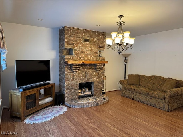 living room featuring a brick fireplace, hardwood / wood-style floors, and a notable chandelier