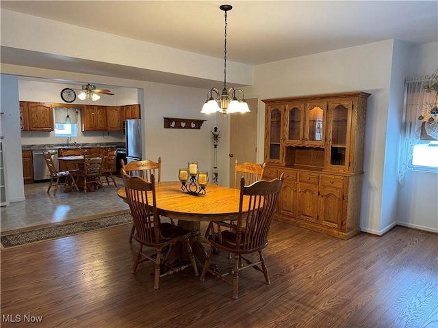 dining area featuring ceiling fan with notable chandelier, dark hardwood / wood-style flooring, and sink