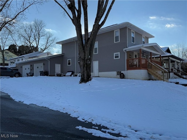 snow covered property featuring a porch and a garage