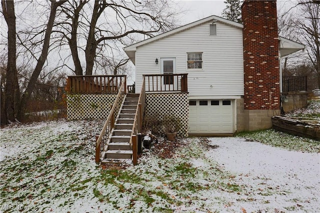 snow covered rear of property with a garage and a deck