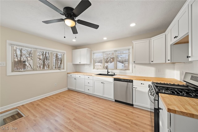 kitchen featuring white cabinets, sink, ceiling fan, appliances with stainless steel finishes, and butcher block countertops