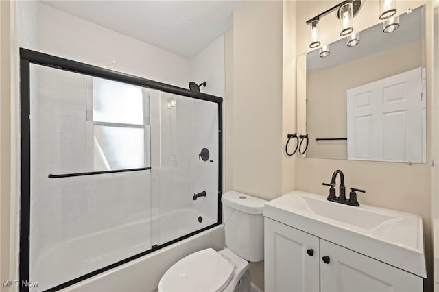 full bathroom with vanity, bath / shower combo with glass door, and toilet