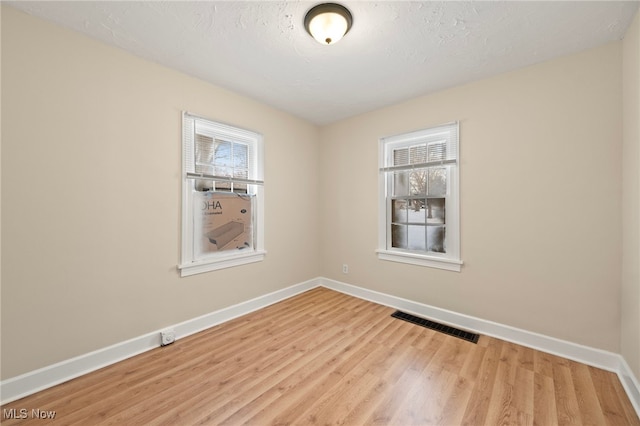 spare room with light hardwood / wood-style floors and a textured ceiling