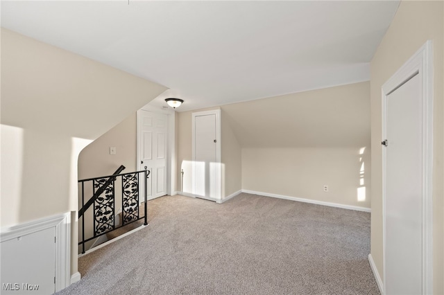 bonus room with light colored carpet and vaulted ceiling