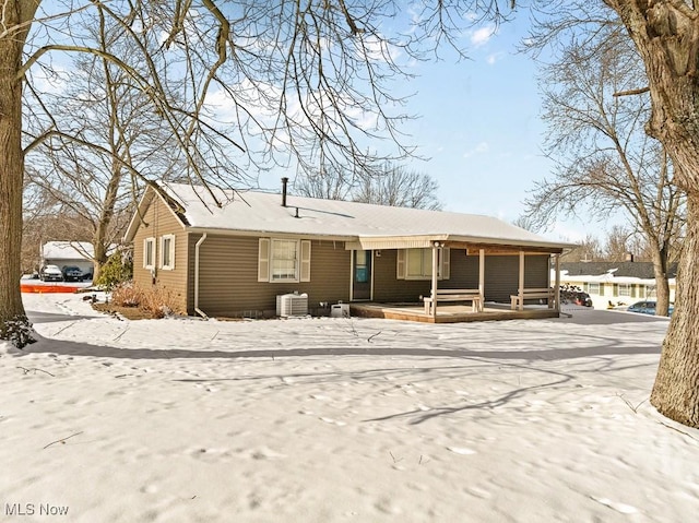 snow covered property with covered porch and central AC unit