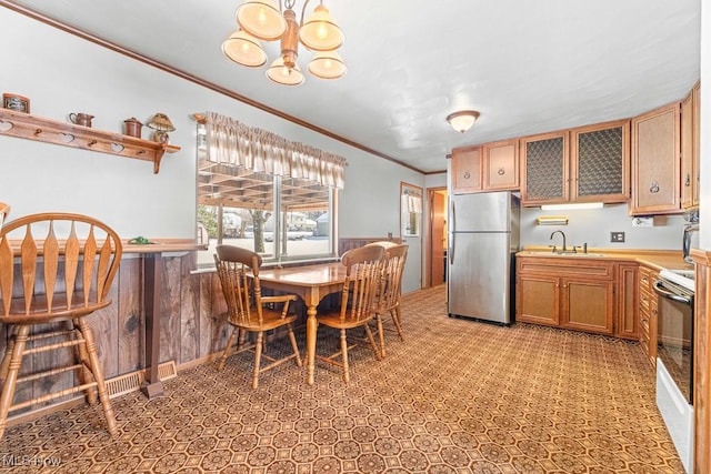 kitchen with white electric stove, sink, a notable chandelier, stainless steel refrigerator, and crown molding