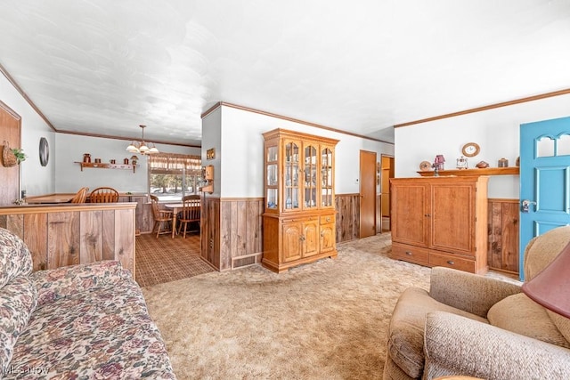 living room featuring carpet floors, ornamental molding, a chandelier, and wooden walls