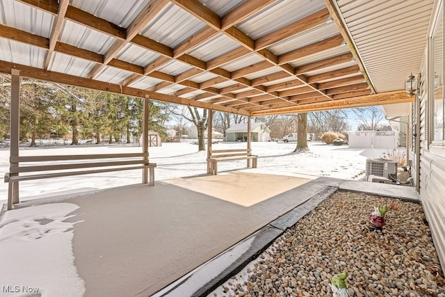 snow covered patio with a storage shed and cooling unit