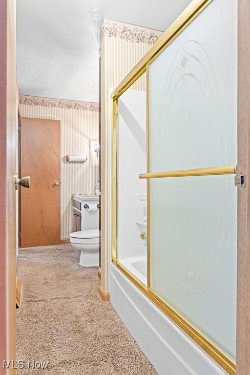 bathroom featuring shower / bath combination with glass door and toilet