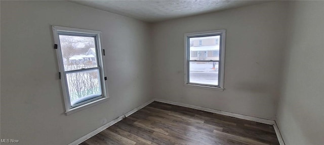 unfurnished room featuring a textured ceiling, plenty of natural light, and dark hardwood / wood-style floors