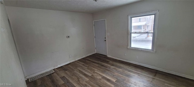 spare room with dark hardwood / wood-style flooring, a healthy amount of sunlight, and a textured ceiling