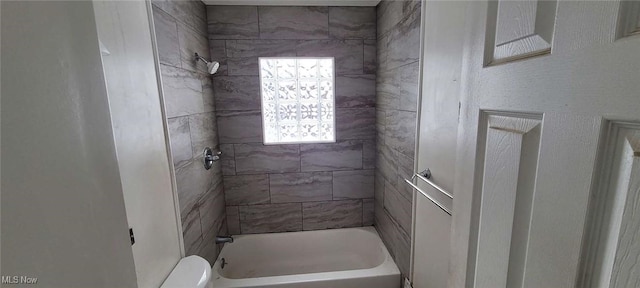 bathroom with tiled shower / bath combo and toilet