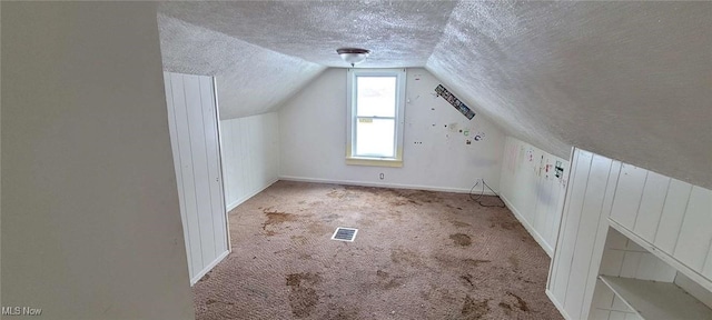 bonus room with vaulted ceiling, light carpet, and a textured ceiling