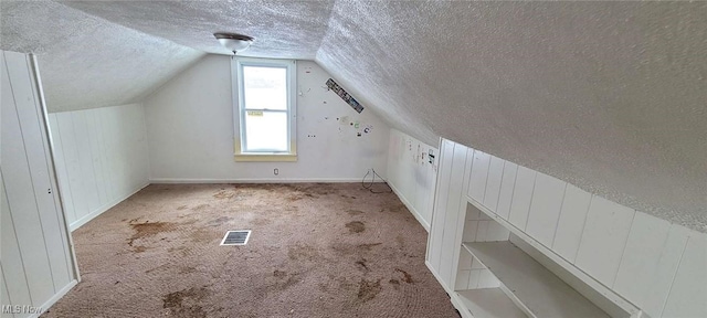 bonus room with lofted ceiling, a textured ceiling, and light carpet