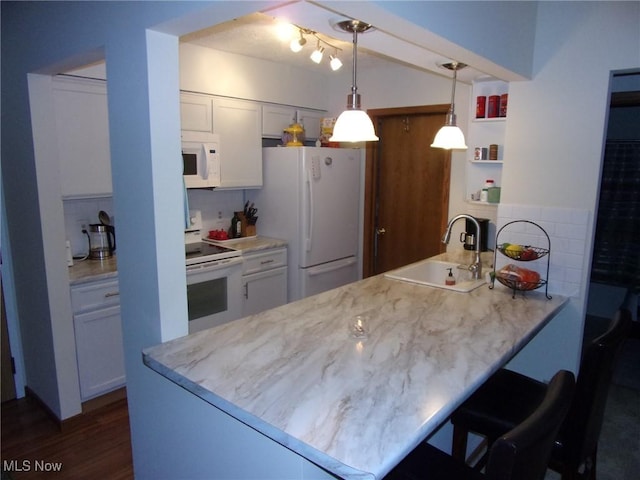 kitchen with sink, kitchen peninsula, pendant lighting, white appliances, and white cabinets