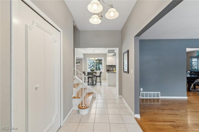 hallway with light tile patterned floors and an inviting chandelier