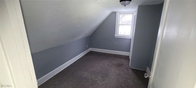 additional living space with dark carpet and vaulted ceiling