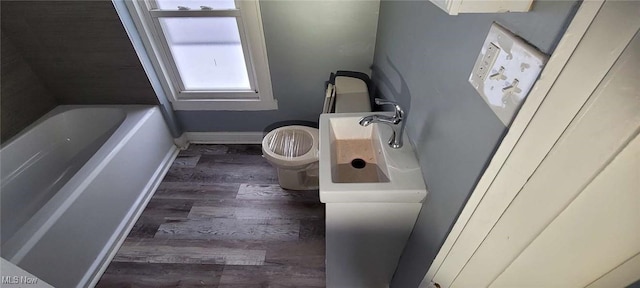 bathroom featuring hardwood / wood-style floors, vanity, a bath, and toilet