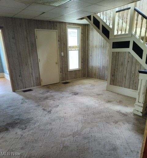 unfurnished room with wood walls and light colored carpet