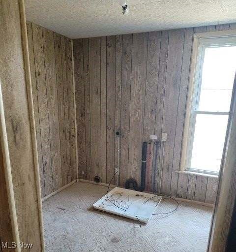 spare room with a textured ceiling and wooden walls