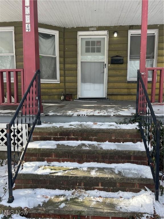 snow covered property entrance featuring a porch