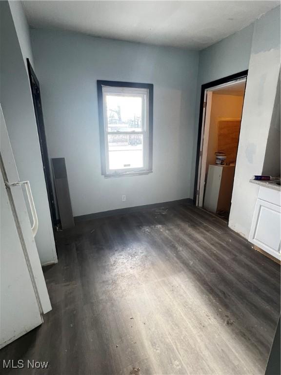 unfurnished bedroom featuring white refrigerator and dark hardwood / wood-style floors