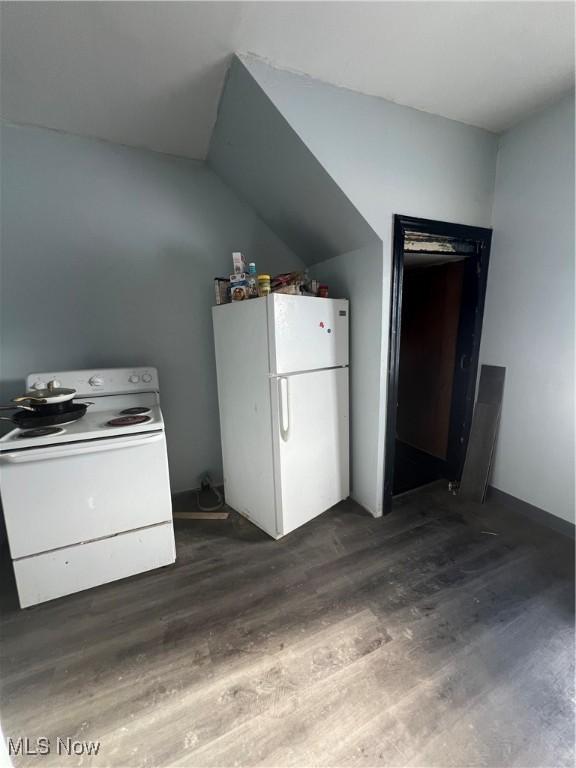 kitchen with white appliances, vaulted ceiling, and dark hardwood / wood-style floors