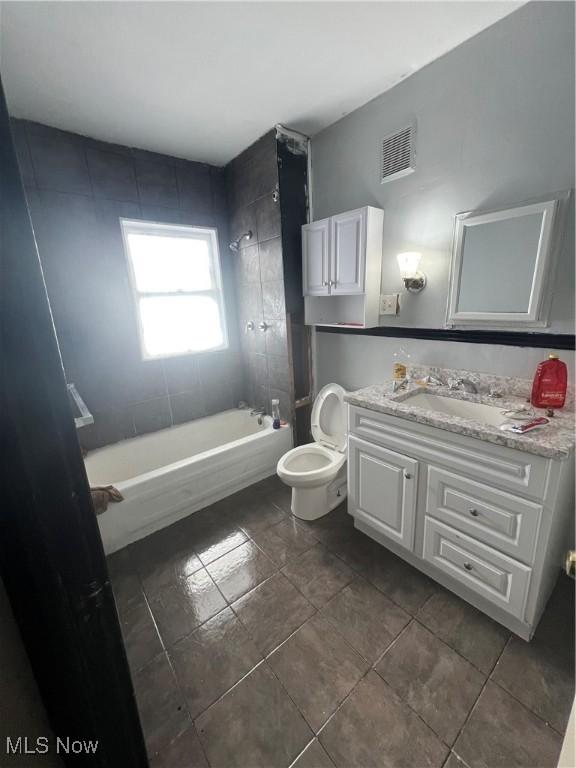 full bathroom with tiled shower / bath, vanity, and toilet