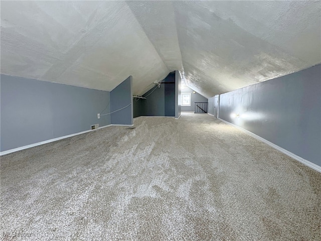 additional living space featuring a textured ceiling, carpet floors, and lofted ceiling