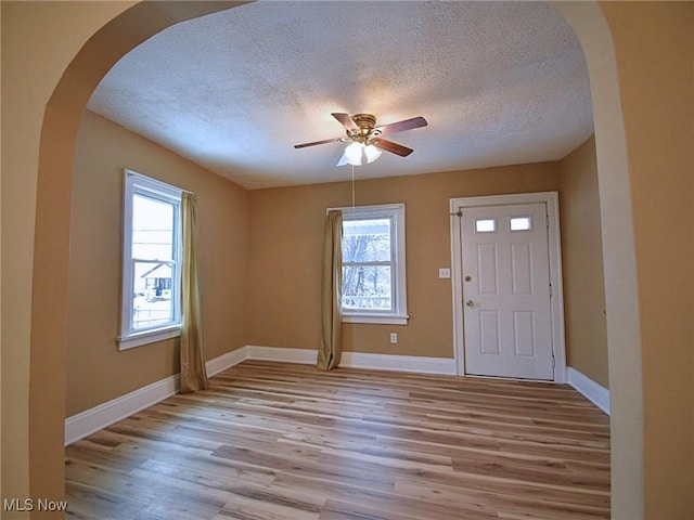 foyer entrance featuring a wealth of natural light, light hardwood / wood-style flooring, ceiling fan, and a textured ceiling