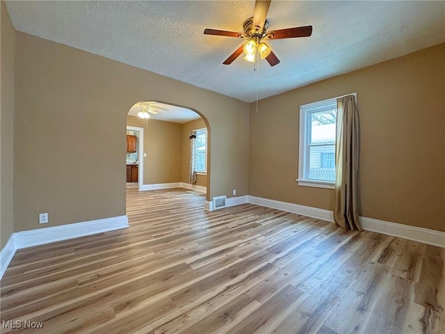 spare room featuring a textured ceiling, light hardwood / wood-style flooring, and ceiling fan