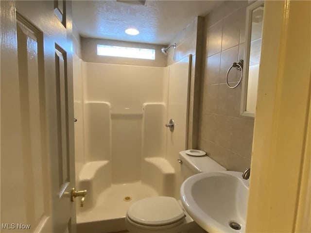 bathroom featuring a shower, sink, a textured ceiling, and toilet