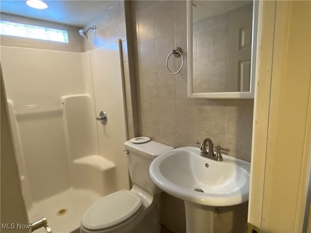 bathroom with backsplash, toilet, walk in shower, and sink