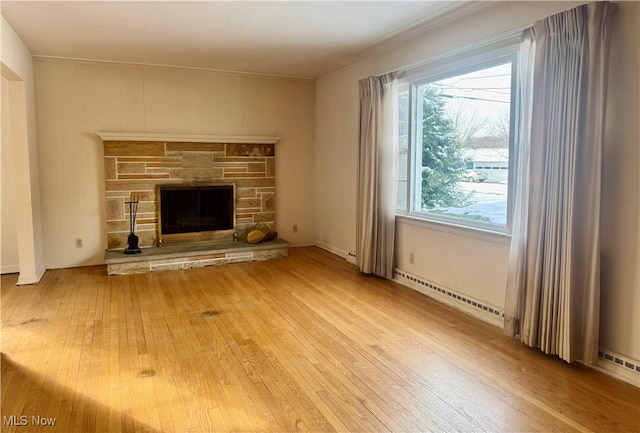 unfurnished living room with a stone fireplace, wood-type flooring, and a baseboard radiator