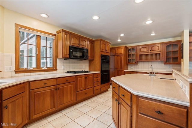 kitchen featuring tasteful backsplash, sink, light tile patterned floors, and black appliances