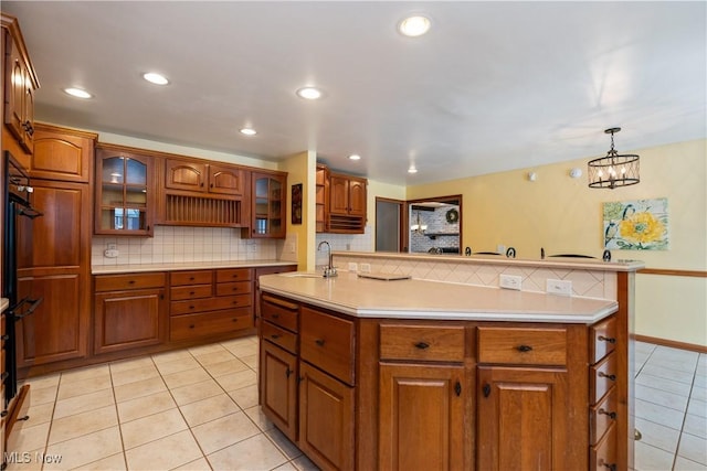 kitchen featuring pendant lighting, sink, decorative backsplash, light tile patterned flooring, and a chandelier