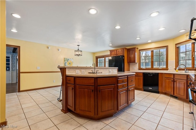 kitchen featuring hanging light fixtures, decorative backsplash, a kitchen island with sink, light tile patterned flooring, and black appliances