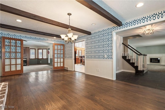 interior space with french doors, a brick fireplace, dark hardwood / wood-style floors, a notable chandelier, and a textured ceiling