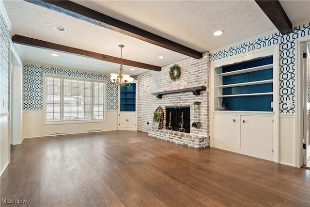 unfurnished living room with a fireplace, built in features, a chandelier, and a textured ceiling