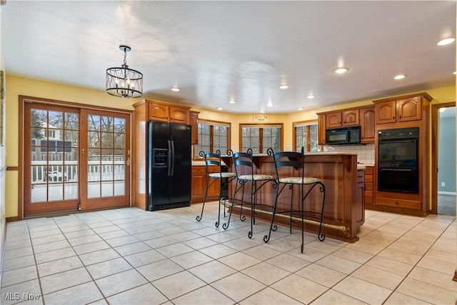 kitchen featuring black appliances, a center island, light tile patterned floors, and backsplash