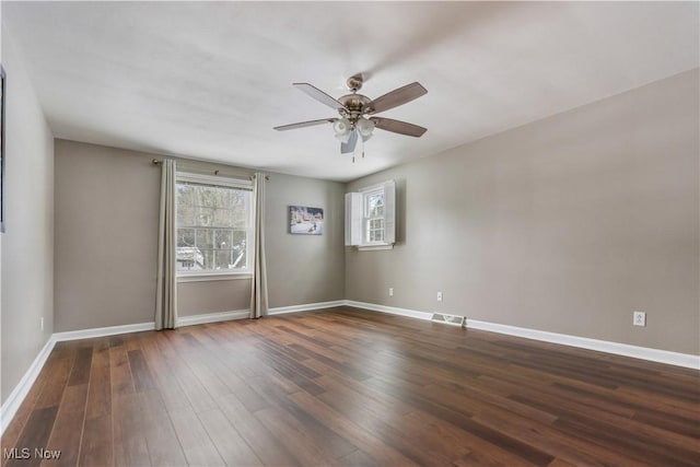 spare room featuring dark hardwood / wood-style floors, ceiling fan, and a wealth of natural light